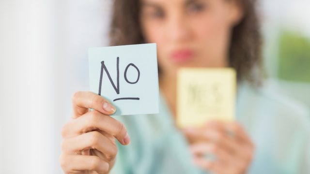 Portrait of a smiling businesswoman holding yes and no sticks