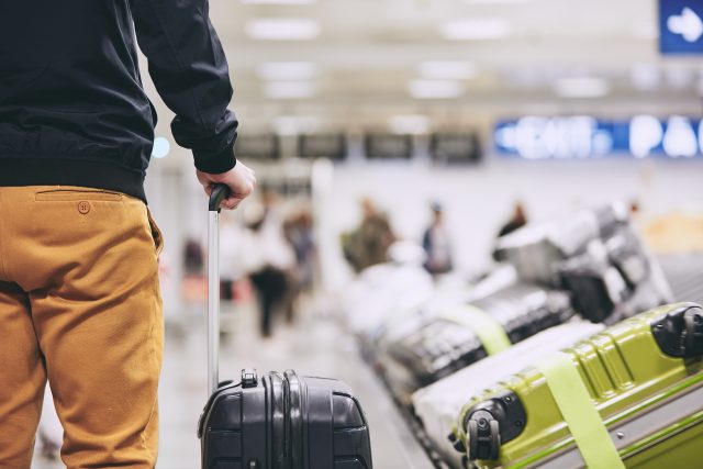 Man,Traveling,By,Airplane.,Young,Passenger,Holding,His,Suitcase,Near