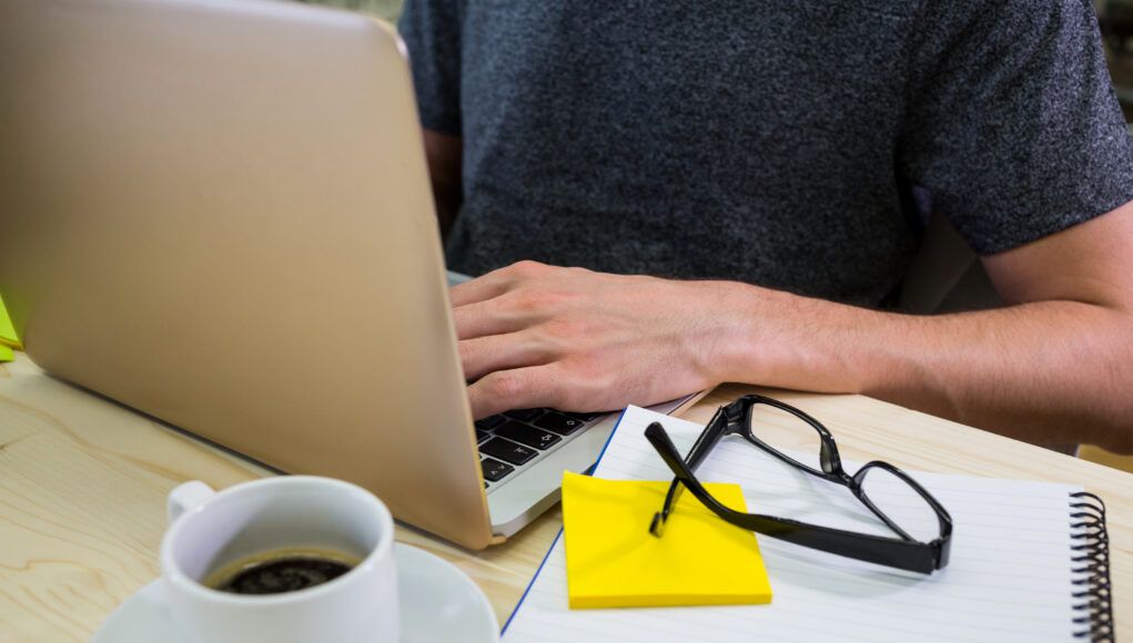 Mid-section of male business executive using laptop
